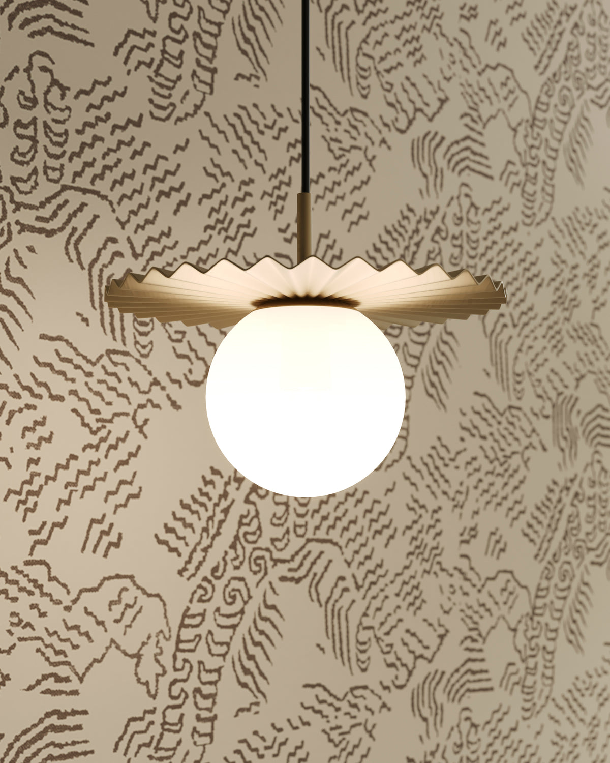 Brushed gold pendant with a pleated metal shade and glowing globe light set against patterned wallpaper.
