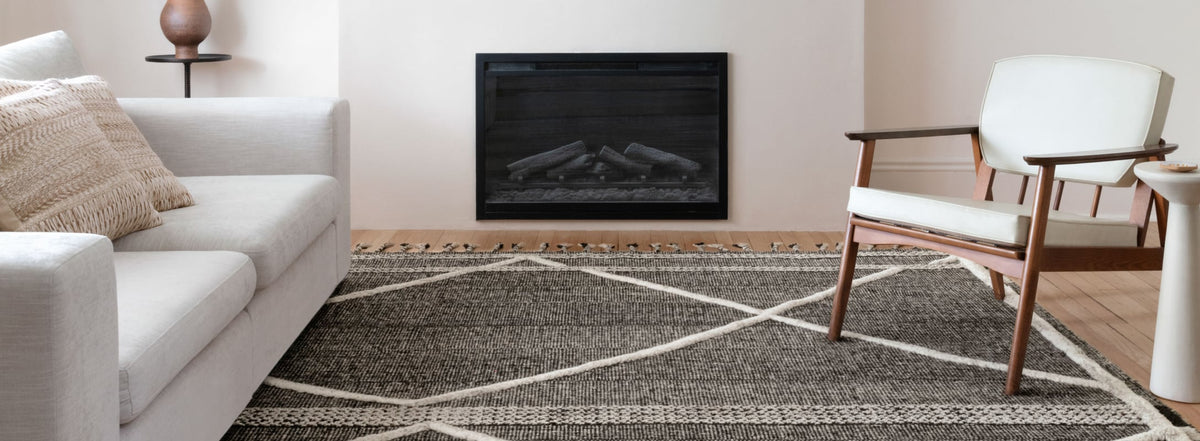 Modern living room featuring a dark woven area rug with white geometric accents, paired with neutral furniture and a cozy fireplace.